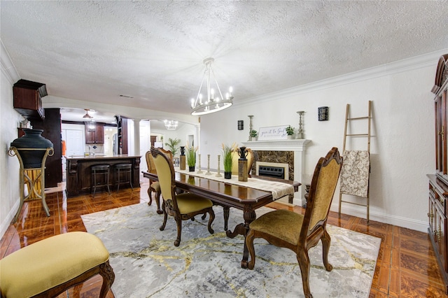 tiled dining room featuring a premium fireplace, a notable chandelier, decorative columns, crown molding, and a textured ceiling