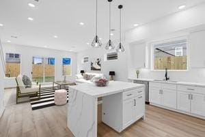 kitchen featuring pendant lighting, white cabinets, sink, light hardwood / wood-style floors, and a kitchen island