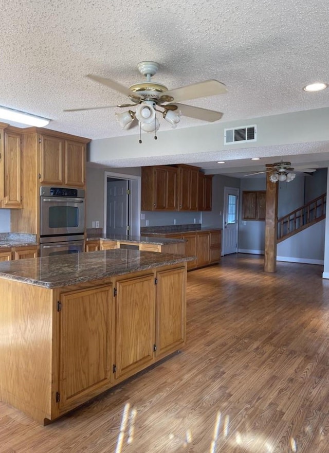 kitchen with a textured ceiling, stainless steel double oven, and hardwood / wood-style floors