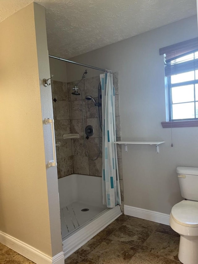 bathroom with curtained shower, toilet, and a textured ceiling