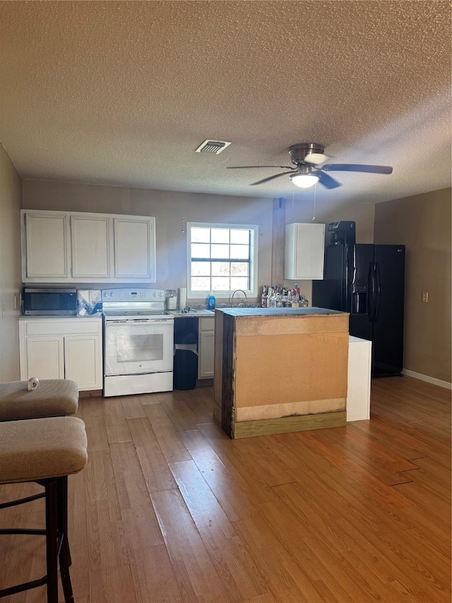 kitchen with black fridge, a textured ceiling, electric stove, light hardwood / wood-style flooring, and white cabinetry