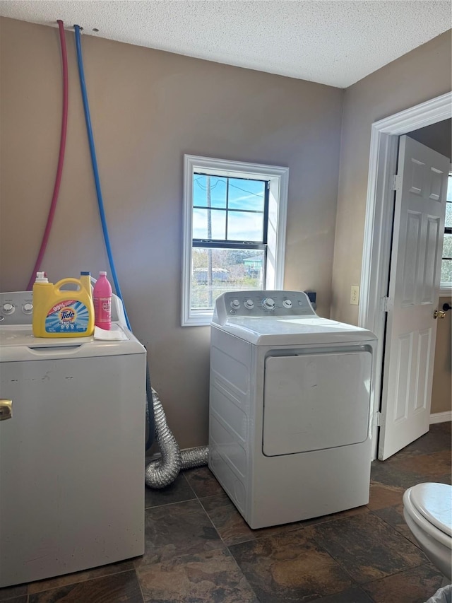 washroom with a textured ceiling and independent washer and dryer