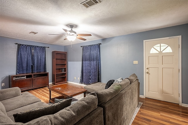 living room featuring ceiling fan, hardwood / wood-style floors, and a textured ceiling