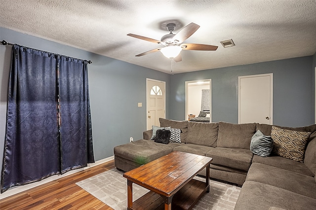 living room with wood-type flooring, a textured ceiling, and ceiling fan