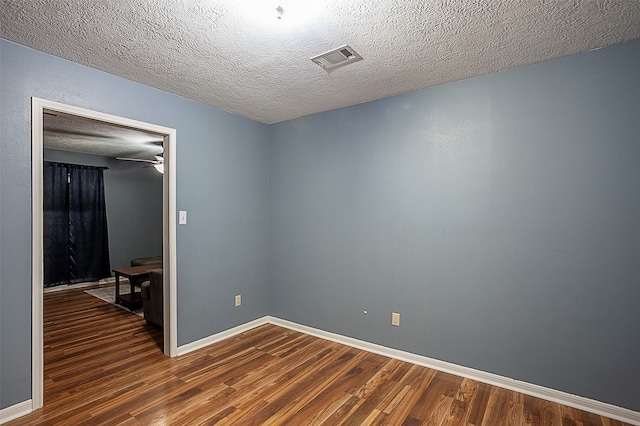 empty room with a textured ceiling, dark hardwood / wood-style flooring, and ceiling fan