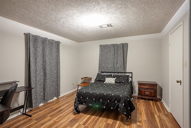 bedroom with a textured ceiling and dark hardwood / wood-style floors