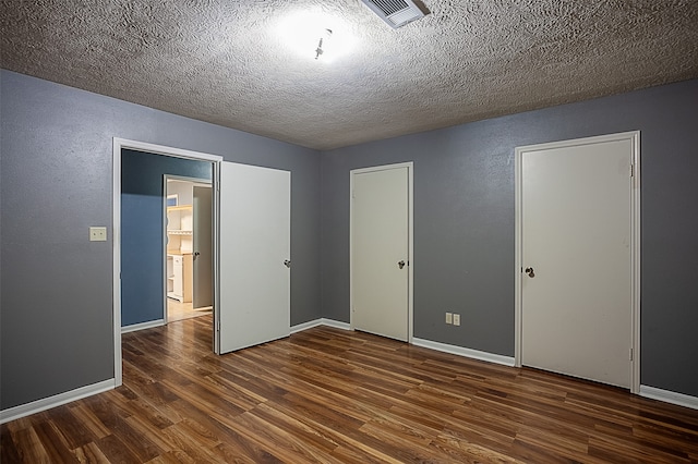 unfurnished bedroom with a textured ceiling and dark hardwood / wood-style flooring