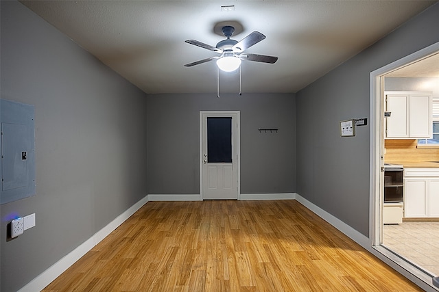 spare room with ceiling fan, light wood-type flooring, and electric panel