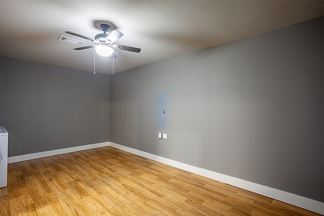 empty room with ceiling fan, washer / dryer, light wood-type flooring, and electric panel