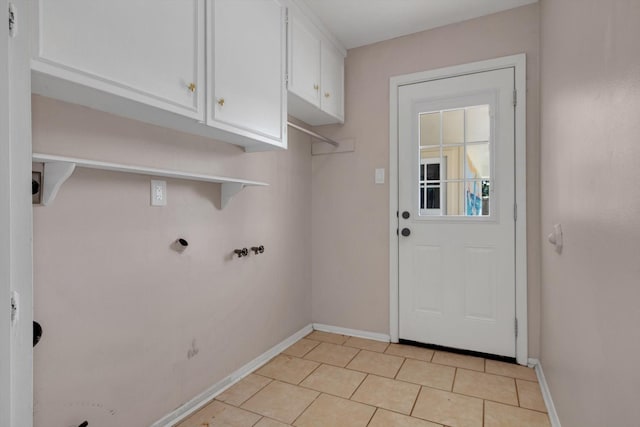 laundry area with gas dryer hookup, light tile patterned floors, and cabinets