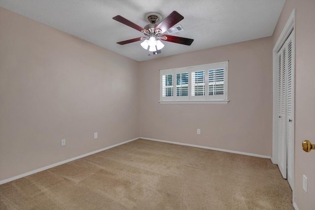 unfurnished bedroom featuring ceiling fan, light colored carpet, and a closet