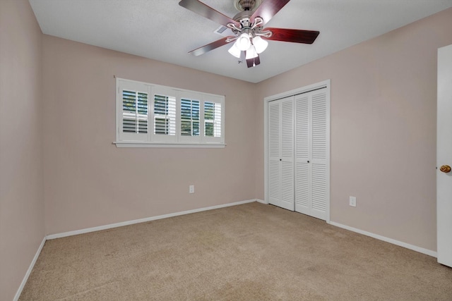 unfurnished bedroom with ceiling fan, light carpet, and a closet