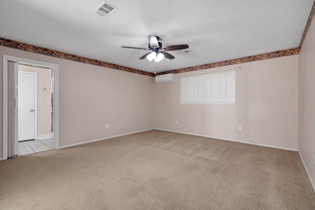 spare room with a wall mounted AC, ceiling fan, light colored carpet, and a textured ceiling