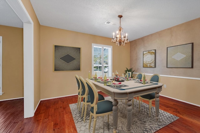 dining space with a chandelier, hardwood / wood-style floors, and a textured ceiling