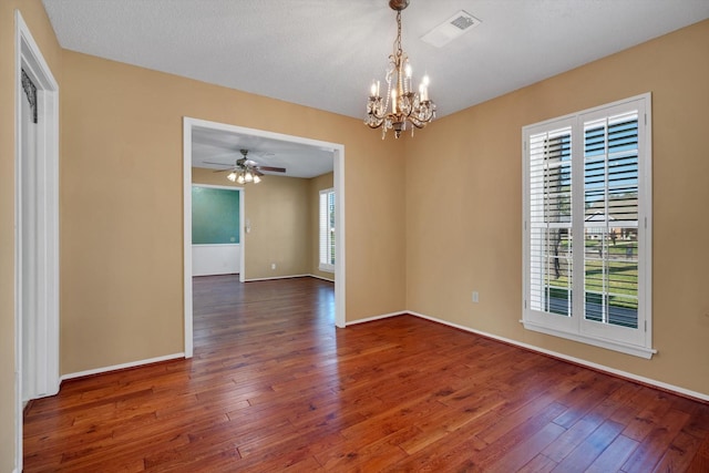 spare room with plenty of natural light, ceiling fan with notable chandelier, and dark hardwood / wood-style floors