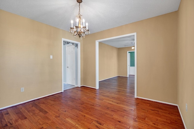 empty room featuring a textured ceiling, ceiling fan with notable chandelier, and hardwood / wood-style flooring