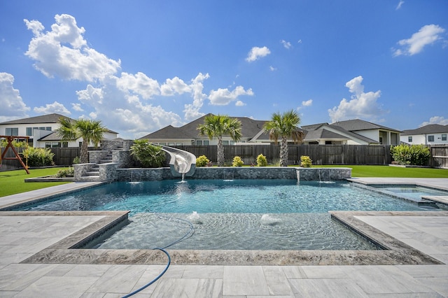 view of pool featuring a lawn, pool water feature, a water slide, and an in ground hot tub