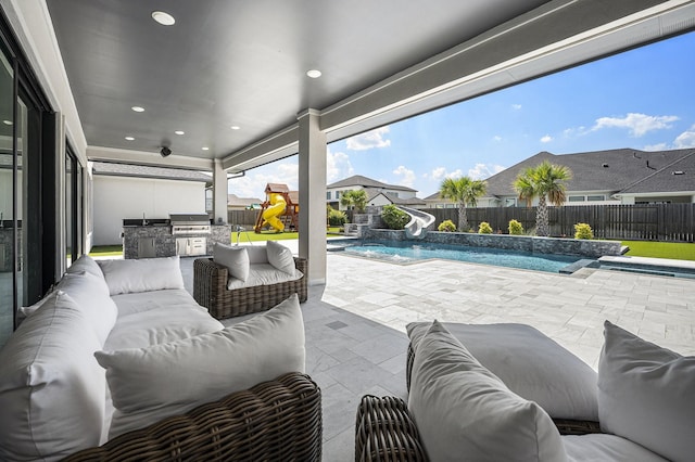 view of patio / terrace with an outdoor kitchen, a fenced in pool, a grill, outdoor lounge area, and pool water feature