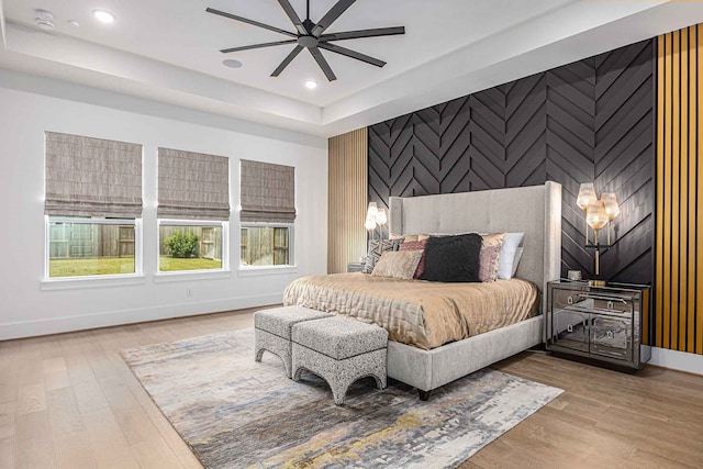 bedroom featuring ceiling fan, hardwood / wood-style flooring, and a raised ceiling