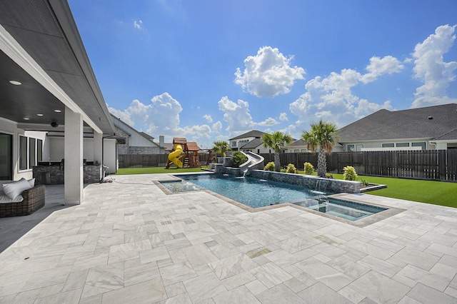 view of swimming pool with a playground, pool water feature, an in ground hot tub, a water slide, and a patio