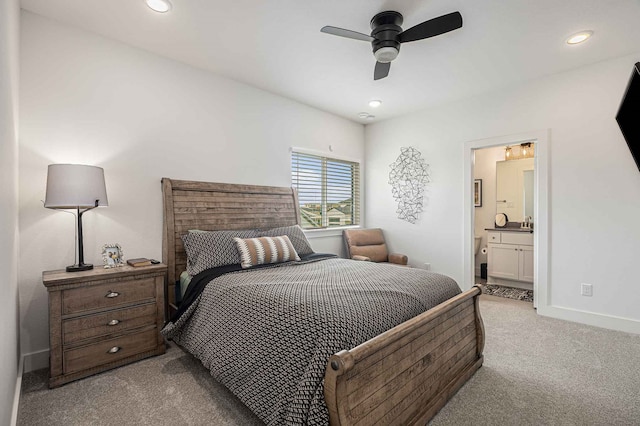 bedroom featuring ceiling fan, light colored carpet, and ensuite bath