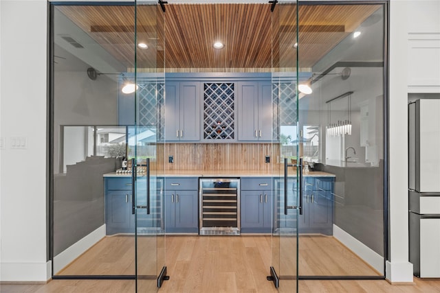 bar with decorative light fixtures, backsplash, stainless steel fridge, beverage cooler, and wooden ceiling