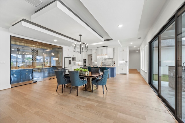 dining space featuring an inviting chandelier, a wealth of natural light, and light hardwood / wood-style flooring