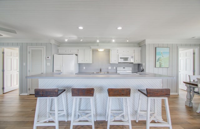 kitchen with a kitchen bar, white cabinetry, sink, and white appliances