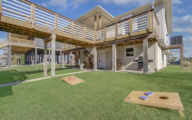 rear view of property featuring a wooden deck, a patio, a lawn, and stairs