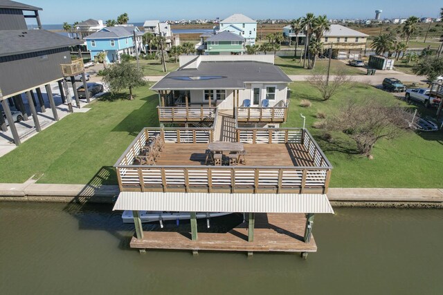 back of property with a yard, a deck with water view, and a residential view