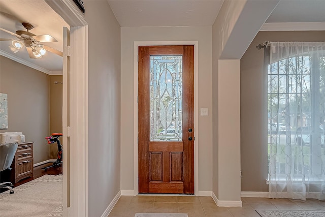 tiled entryway featuring ceiling fan and crown molding