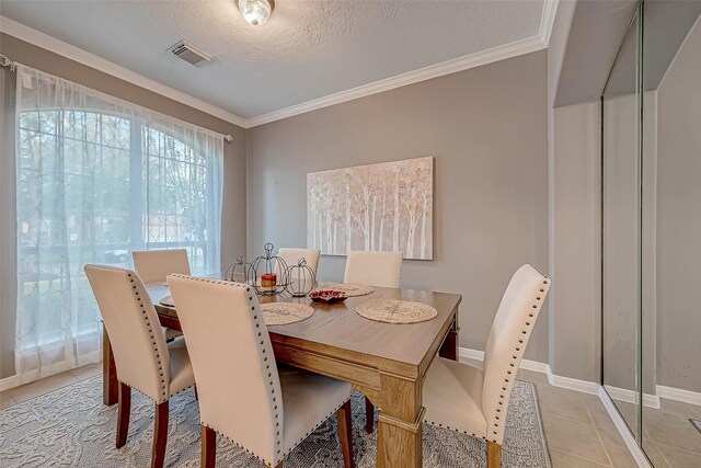 dining space featuring a textured ceiling, ornamental molding, and light tile patterned floors