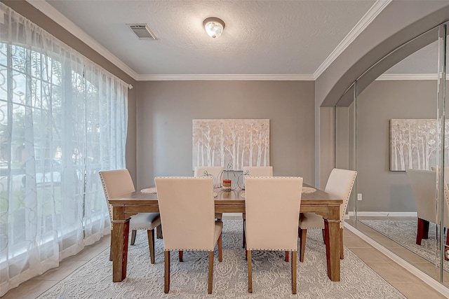 tiled dining area with a textured ceiling and ornamental molding