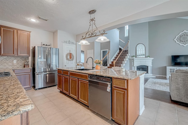 kitchen with an island with sink, appliances with stainless steel finishes, light tile patterned floors, and sink