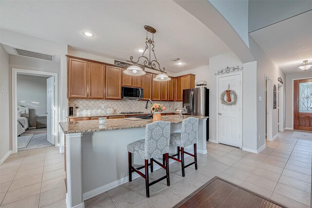 kitchen featuring stainless steel appliances, an island with sink, tasteful backsplash, and light tile patterned floors