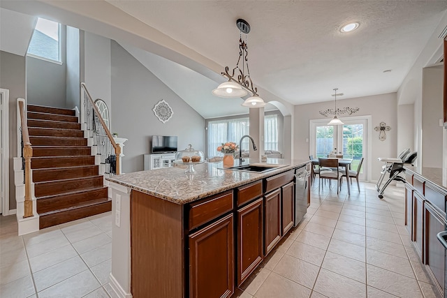 kitchen with stainless steel dishwasher, vaulted ceiling, hanging light fixtures, an island with sink, and sink