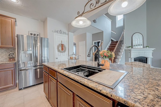 kitchen featuring light tile patterned floors, light stone counters, stainless steel refrigerator with ice dispenser, sink, and backsplash