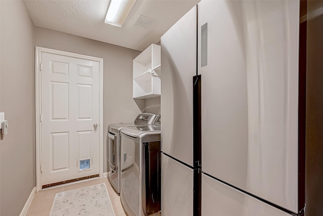 laundry area with washer and clothes dryer and light tile patterned flooring