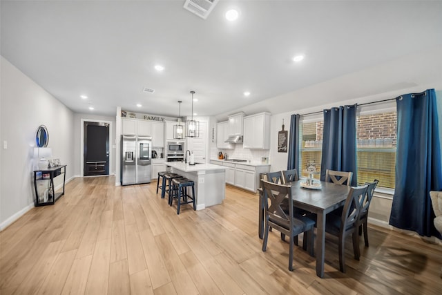 dining space featuring light wood-type flooring and sink