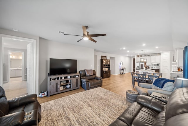 living room with ceiling fan, light wood-type flooring, and sink