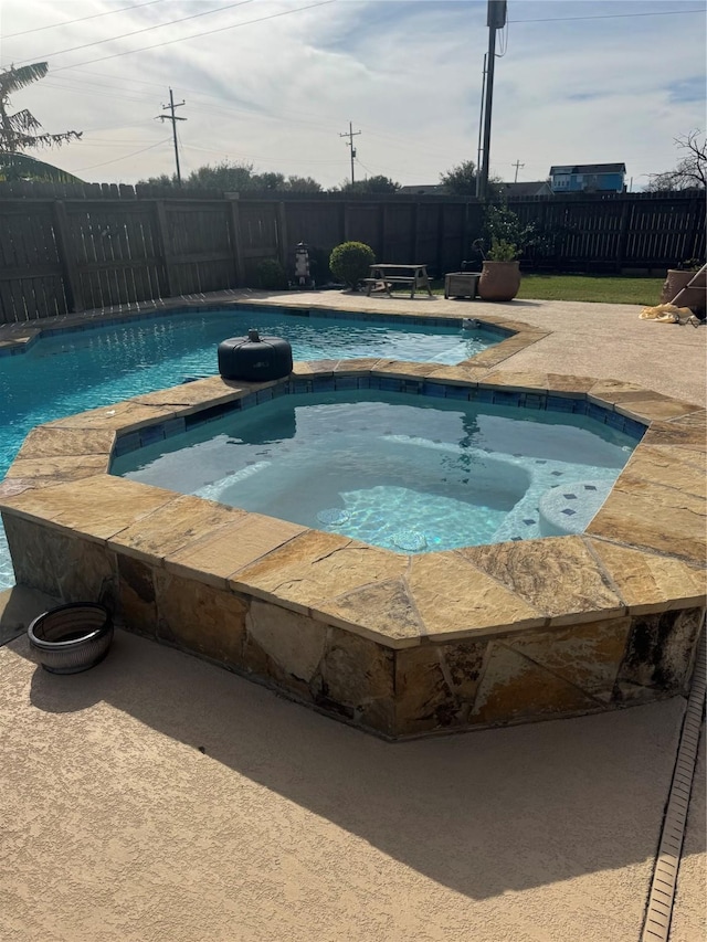 view of swimming pool with an in ground hot tub