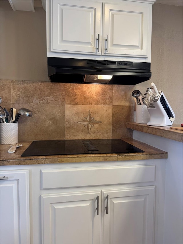 kitchen with ventilation hood, white cabinets, black electric stovetop, and tasteful backsplash