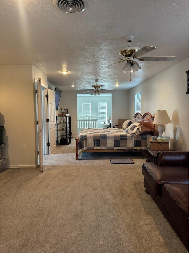 carpeted bedroom featuring ceiling fan and a textured ceiling