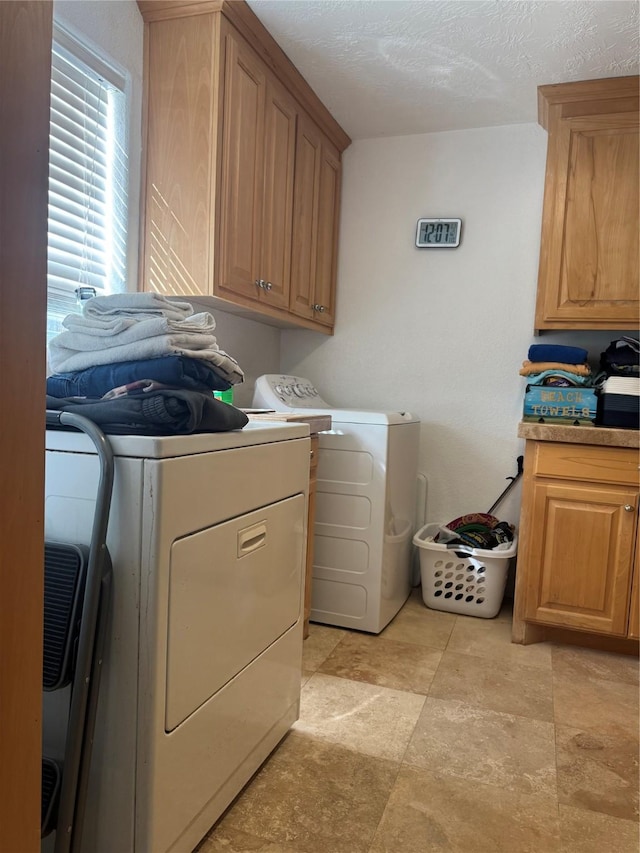 laundry area with cabinets, a textured ceiling, and washing machine and dryer