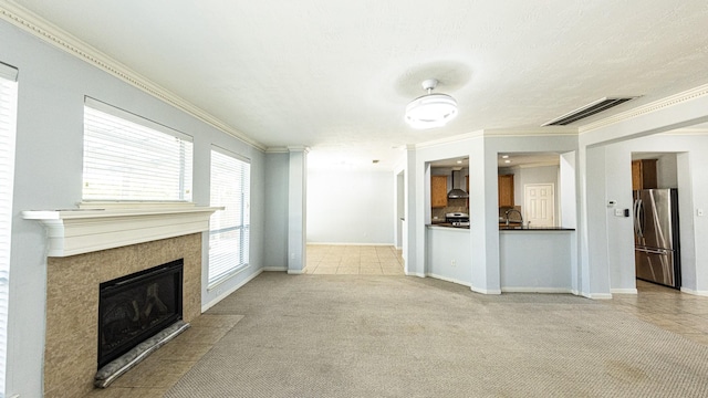 unfurnished living room with light carpet, sink, ornamental molding, and a tiled fireplace