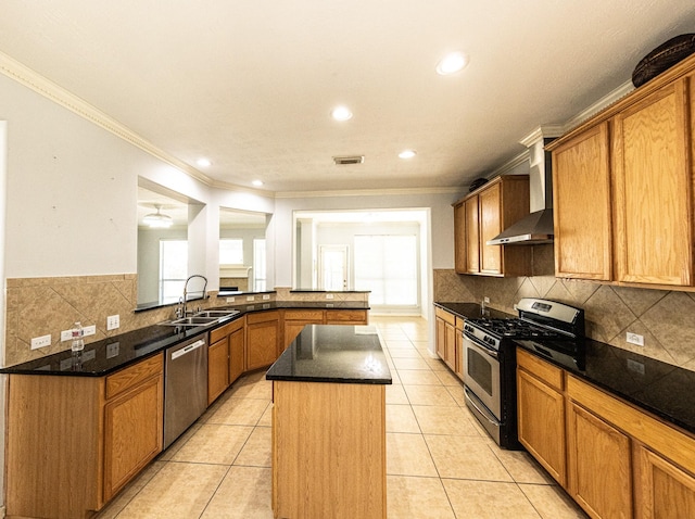 kitchen featuring sink, stainless steel appliances, wall chimney range hood, a kitchen island, and light tile patterned flooring