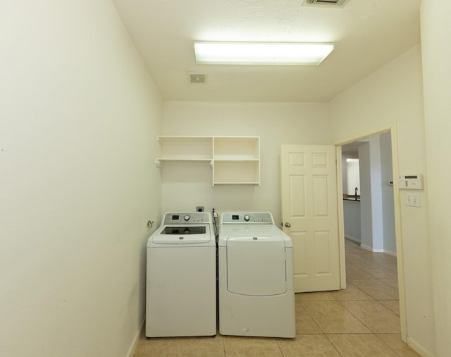 laundry area with washer and dryer and light tile patterned floors