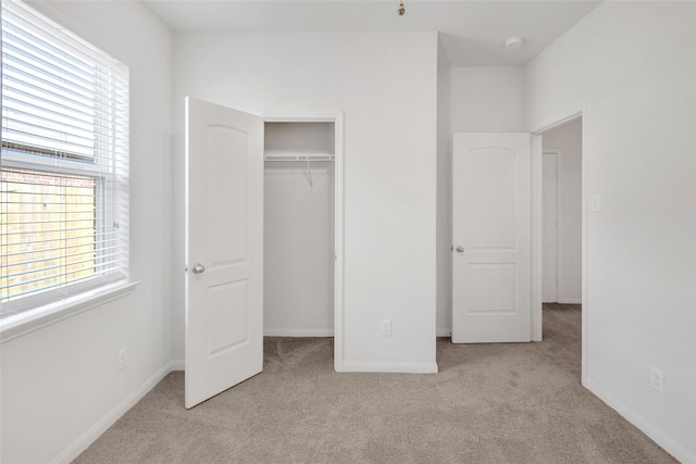 unfurnished bedroom featuring light carpet, multiple windows, and a closet