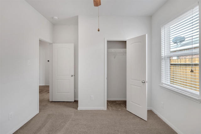 unfurnished bedroom with light colored carpet, a closet, and ceiling fan