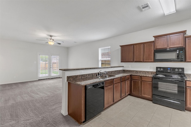 kitchen featuring sink, kitchen peninsula, dark stone counters, light colored carpet, and black appliances